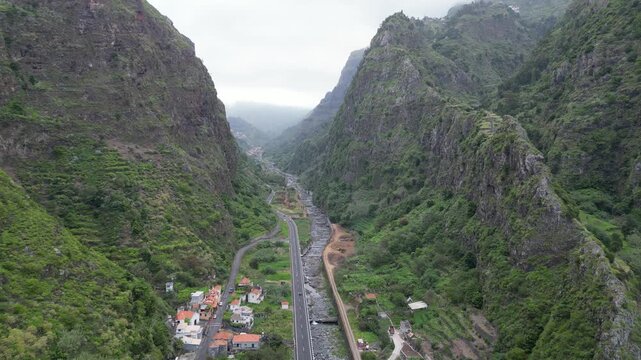Descending aerial push-in through deep green Sao Vicente mountain valley in Madeira