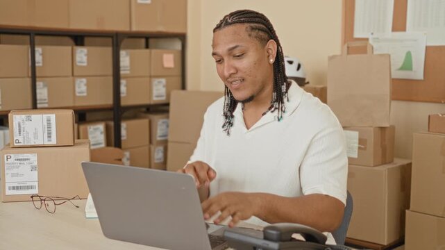 Man writing in a notebook with laptop and parcels at a desk inside a building mailroom; small business focus.