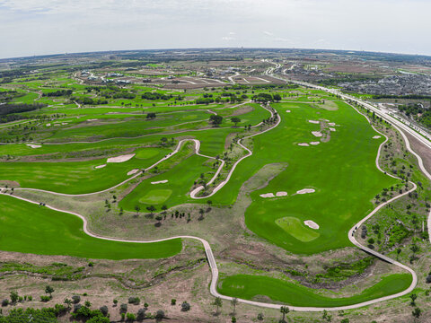 Aerial view of a lush green golf course with winding fairways, sand bunkers, and surrounding residential development in Frisco, TX, United States.