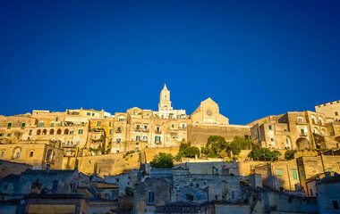 Fototapeta premium Matera. Panoramic view of golden hour sunset at Sassi di Matera in Italy, historic Sassi cave dwellings and ancient stone architecture in Basilicata