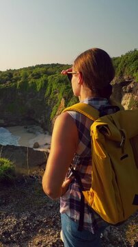 Vertical video. Female Traveler Admiring Hidden Coastal Cove and Turquoise Ocean From High Cliff at Korawa Beach in Slow Motion