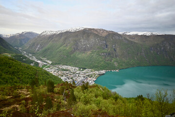 Obraz premium Panoramic view of Høyanger, Norway from a mountain above the fjord, showing the town, valley, turquoise water, and surrounding rocky cliffs.