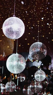 Vertical video. Mirrored disco balls suspended above the dance area as decor for a wedding.