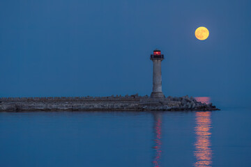 Naklejka premium Full strawberry moon rising behind Trakata lighthouse near Euxinograd in Varna Bulgaria
