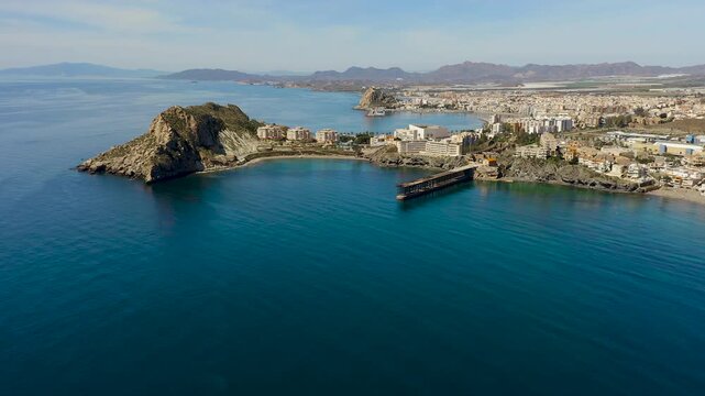 Aerial view of Aguilas city in Murcia, Spain, featuring Levante Bay and marina. Coastal urban landscape with calm Mediterranean waters, harbor structures and scenic shoreline.