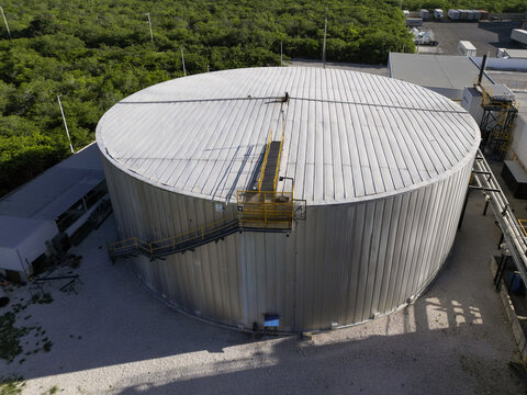 Aerial view of the Ergon Asfaltos Progreso industrial storage tank, featuring a large metallic cylindrical structure with a staircase, surrounded by vegetation in Progreso, Yucatan, Mexico.