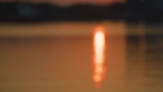 Abstract blurred sunset reflection glowing on calm evening water