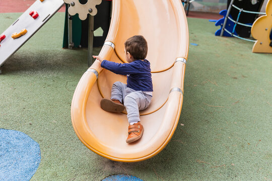 Child sliding down playground slide outdoors