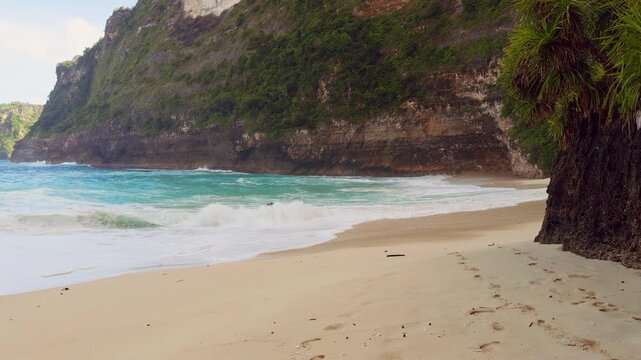 Powerful Wave Surging Across the Shoreline at Kelingking Beach Beneath Sunlit Limestone Cliffs in Slow Motion