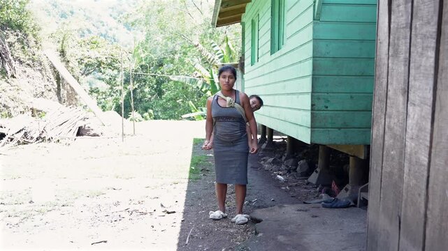 Indigenous mother carrying her child on her back in a rural village