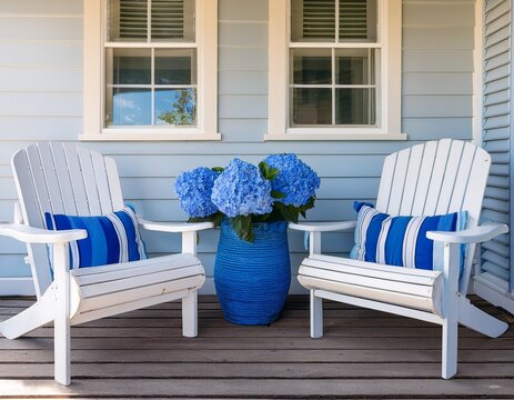 white adirondack chairs and table on wooden porch with blue hydrangeas and pots coastal cottage outdoor seating area with blue striped cushions and bright blue vases