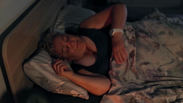 Overweight Older Female Sleeping and Adjusting Position in Bed at Night