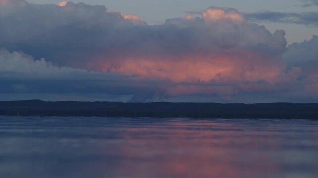 Surface of the river with calm waves and pink clouds in the sky