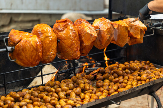 Roasting pork hocks and potatoes on a rotisserie at a street event