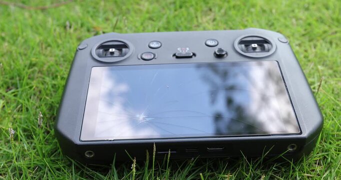 Broken drone remote controller on the green grass