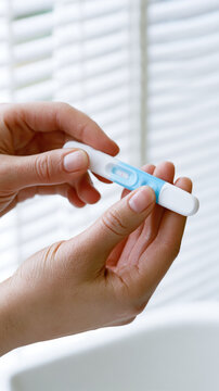 Ovulation test hand plastic device closeup female fertility positive bathroom sunlight