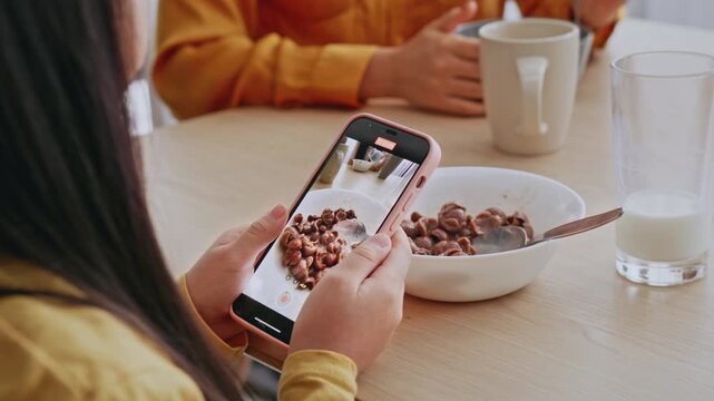 Focused Unrecognizable Person Taking Photo Of Bowl Filled With Cereal While Sitting At Kitchen Table With Milk And Coffee, Engaging In Healthy Eating Concept.