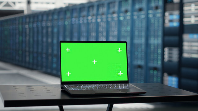 Green screen laptop supports infrastructure maintenance, hardware checks and downtime prevention in a server room.