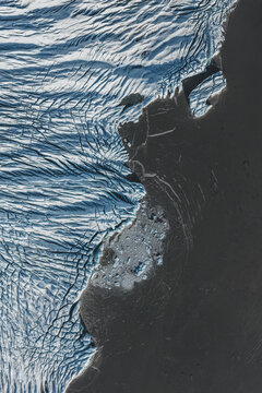 Aerial view of the textured surface of a glacier with deep crevasses and ice formations in Iceland.
