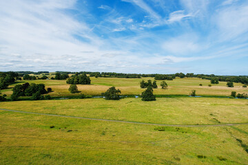 Fototapeta premium Aerial landscape over rural fields with trees and blue sky, UK