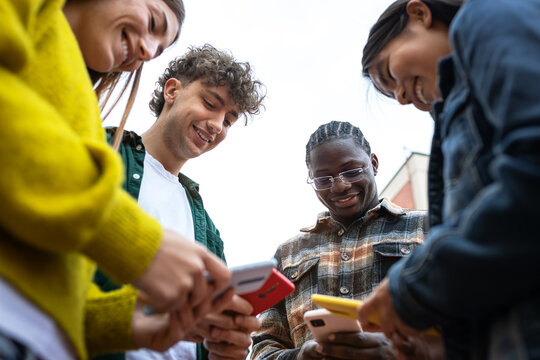 Group of students using smartphones and enjoying time together outdoors
