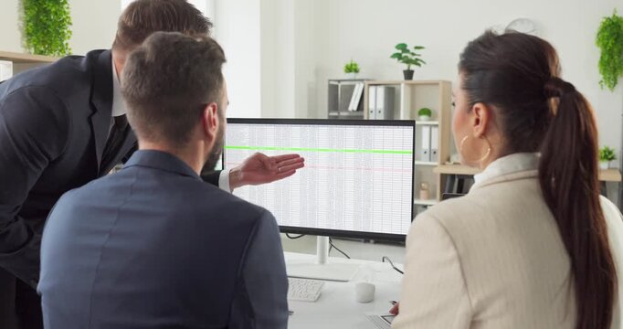 Team colleagues managers meeting analysis strategy discussion. Three professionals review data on a computer monitor in a bright office, evaluating reports. Clear data driven teamwork concept.