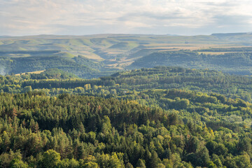 Obraz premium Layers of green mountains and hills in the haze during sunset. Panoramic View of Green hills and Meadow.