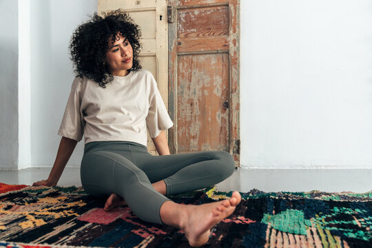 Woman relaxing on colorful rug feeling thoughtful and free