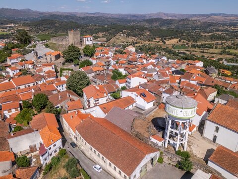 Aerial view of the historic town of Belmonte, featuring its medieval castle, traditional red-tiled rooftops, and a prominent water tower in Belmonte, Castelo Branco District, Portugal.