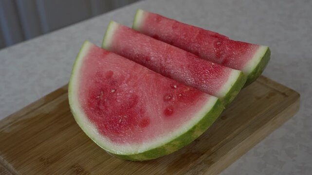 Neatly sliced fresh watermelon wedges on wooden board. Summer fruit presentation. Juicy texture and bright colors of summer produce, making it ideal for food-related content, recipe demonstrations.