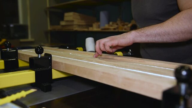 Person worker using a rubber mallet levels a wood of planks. The process of gluing a wood of planks. Furniture renovation concept.