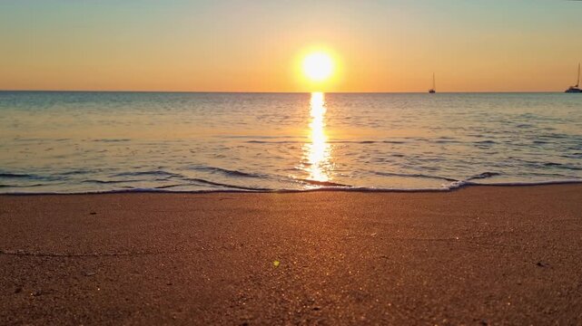 Beautiful sunset by the sea with calm waves, golden sand and bright sky colors, in Sardinia, Italy