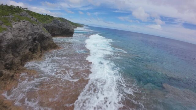 Drone flight along the volcanic coastline of Niue with turquoise natural pools