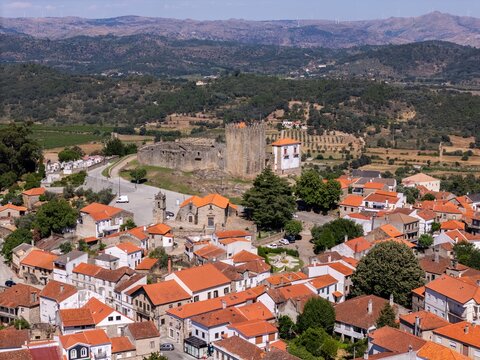 Aerial view of the historic Castle of Belmonte surrounded by traditional terracotta-tiled rooftops and rolling hills in Belmonte, Castelo Branco District, Portugal.