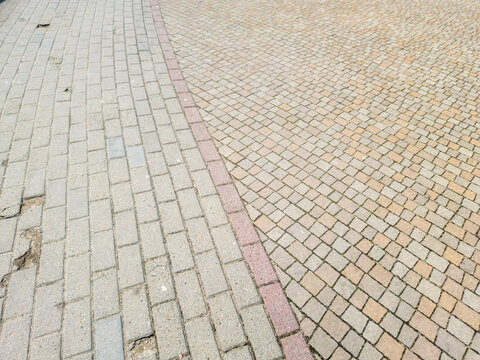 Textured paving stones forming a curved path merging two different styles, highlighting urban design and street aesthetics in a public space.