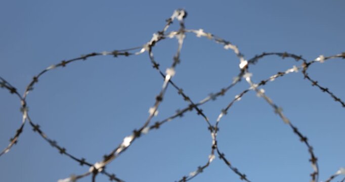 Sharp barbed wire made of metal against a clear sky, stretched barbed wire acts as a security element of the perimeter