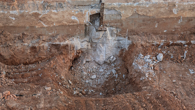 Exposed concrete foundation and excavated ground during structural demolition and site preparation. Earth removal, excavation work, civil engineering, urban redevelopment, construction soil, dirt.