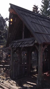 A wooden structure is located in a wooded area. Lanterns hang from the roof. The sun shines brightly, revealing details of the wood and surroundings.