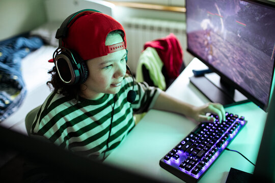 Teen gamer with headset playing pc game at home