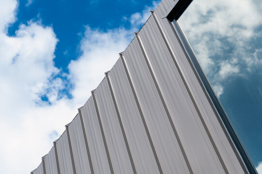 white metal and glass mirror wall modern part of building architecture with cloudy blue sky background	