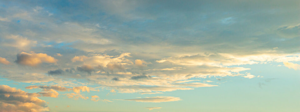 Beautiful sunset sky background with dramatic golden light on soft cumulus clouds for panoramic travel mockup design