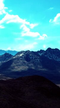 Tall mountains rise in the distance under a clear blue sky. Clouds drift above, casting shadows on the slopes. The landscape shows rocky terrain and distant peaks in sunlight.