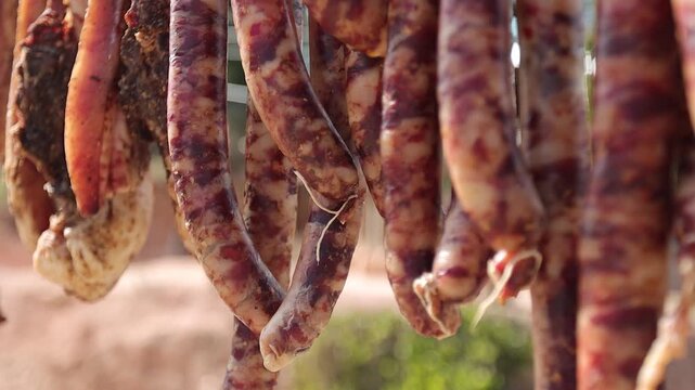 Close-up of traditional Chinese cured pork sausages hanging outdoors to air dry under natural sunlight. Known as Chinese lap cheong, Yunnan sausage, or Sichuan-style cured sausage, this preserved meat
