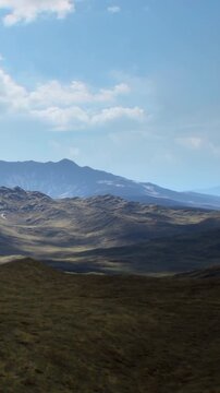 Rolling mountains and open land under a bright sky. The view captures a sense of space and distance with hills stretching into the horizon.