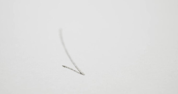 Drawing a check mark on white paper with yellow school pencil.