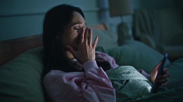 Sad woman crying smartphone bed night closeup. Stressed brunette reading phone