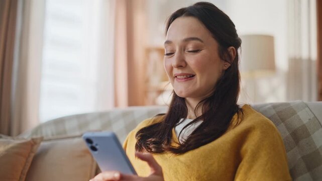 Home woman watching smartphone relaxing couch in cozy apartment interior closeup