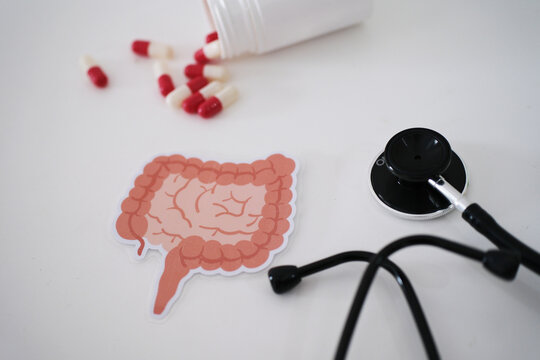 A stethoscope, a symbol of the colon, and pills coming out of a bottle. Treatment and prevention of constipation and diarrhea. The concept of colon and digestive system health. Colon Cancer Awareness 