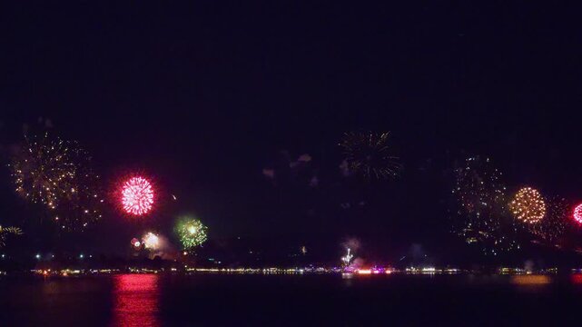Bright New Year Fireworks Bursting Above a Tropical Waterfront at Night With Colorful Reflections Across the Sea, Festive Holiday Atmosphere and Celebration