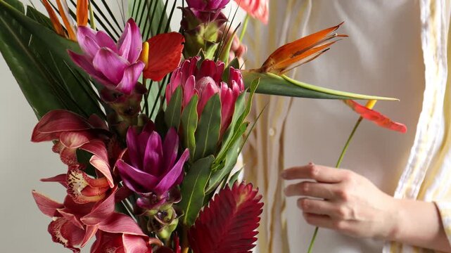 Woman with bouquet of tropical flowers indoors, closeup